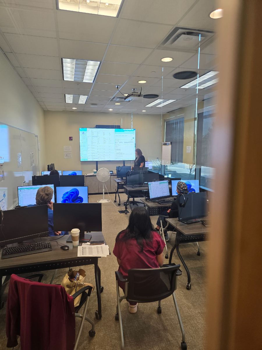 Inside an FSSB training room: trainees at dual-monitor stations with the Epic training environment on the front screen